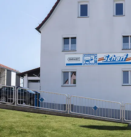 Weißes Wohnhaus mit dem Schild Einfahrt und dem Scharf-Schriftzug an der Fassade.